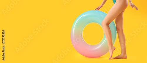 Young woman with inflatable ring on yellow background with space for text