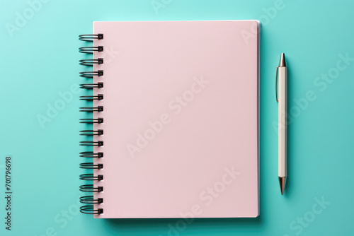 Pink spring-loaded notebook with a pen on a blue background
