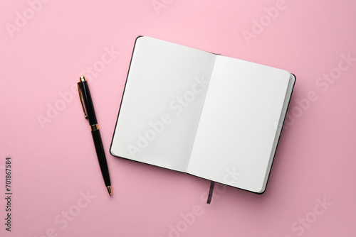 Open notebook with blank pages and pen on light pink background, top view. Space for text