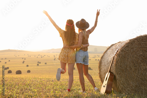 Hippie women near hay bale in field, back view