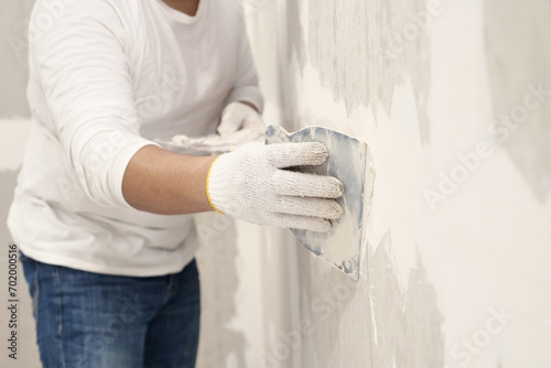 Plasterwork and wall painting preparation. Asian male applying filling drywall patch.