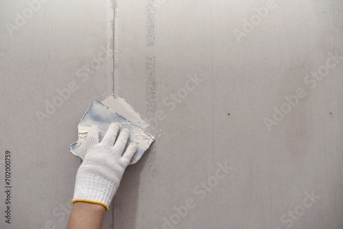 Plasterwork and wall painting preparation. close up hand of craftsman applying filling drywall patch.