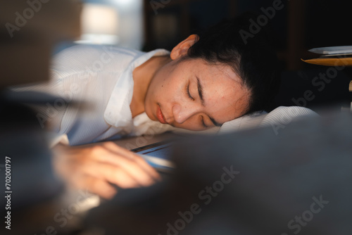 Late-night freelancer, Dedicated Asian woman working overtime on laptop computer, meeting deadlines in the sleepy Night, Businesswoman burning the midnight to working hard, sleep at working desk