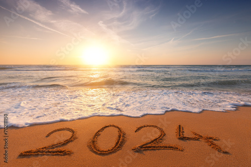2024 Happy New Year on the beach sand, wave and sunrise over tropical island shore background