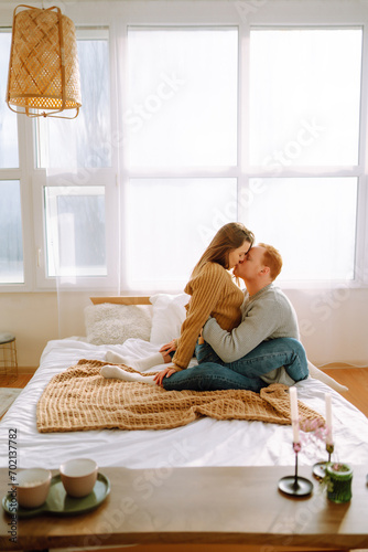 Young couple resting in bed at home. A couple in love spends time together on the bed, hugs each other, gives gifts and has fun. Holiday concept.