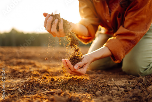 Women's hands sort through black soil in the field. A woman farmer checks the quality of the soil. Ecology, agriculture concept.