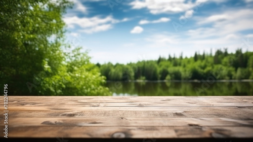 Empty wooden deck with a blurred background of a peaceful lake and lush green forest under a clear sky.