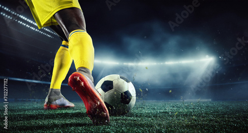 Cropped image of African man's legs, football player in yellow uniform on 3d arena playing, hitting ball. Evening outdoor match. Concept of sport, game, competition, championship. 3D render