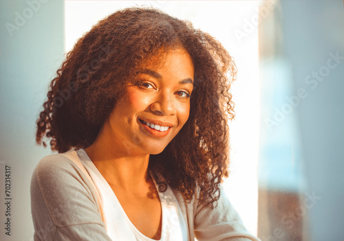 Pleased relaxed African American ethnicity girl in homewear sitting on windowsill