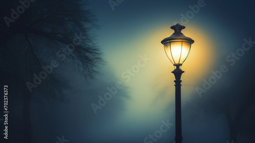 Mystical foggy night with glowing street lamp and silhouette of a leafless tree. Copy space