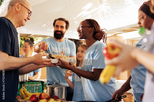 Generous volunteers at food bank, distribute essential items and nourishments to needy. Charity group giving meal donations, serving underprivileged and homeless people with compassion and kindness.