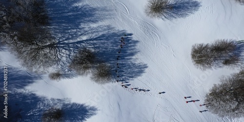 defaulAerial view of a group of hikers with snowshoes proceeding near the frozen and snow-covered Calamone lake on the slopes of Mount Ventasso, Busana, Ramisteo, Reggio Emilia, Italyt
