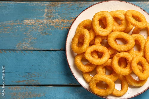 Plate with fried breaded onion rings on blue wooden background