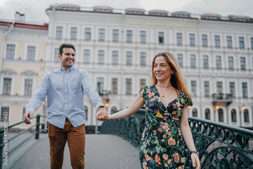 Joyful couple playfully walking hand in hand, laughing together on a picturesque city street