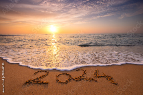 Happy New Year 2024 Text on Tropical Beach Sand, Caribbean sea sunrise and waves on the shore.