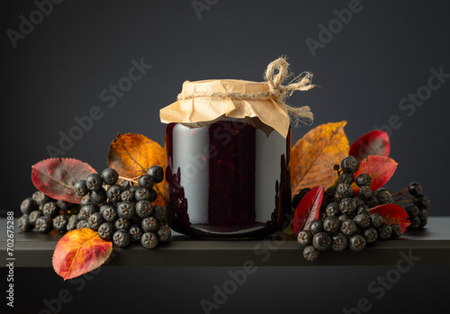 Chokeberry jam and fresh berries with leaves.