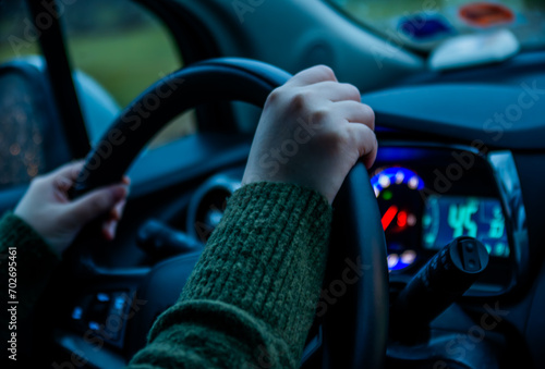 Female driving a modern vehicle in a nighttime setting, hands firmly grasping the steering wheel