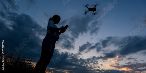 silhouette of woman controlling drone on sunset background