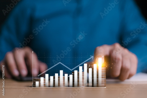 Investment and financial concept, businessman hand with money coin stacking and push arrow up to make a financial growth and profit, interest rates and dividends, investment returns, income, saving.