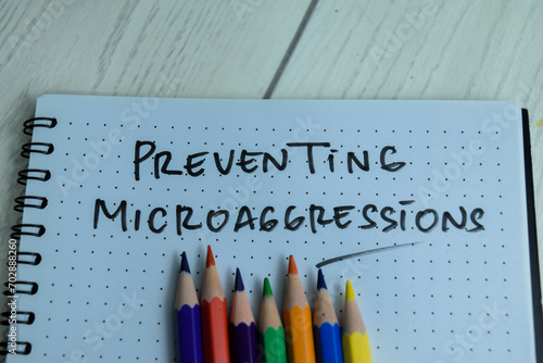 Concept of Preventing Microaggressions write on book isolated on Wooden Table.