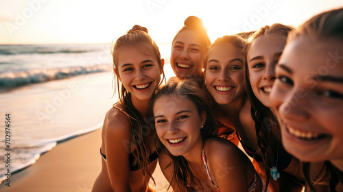 Group of smiling laughing young women posing at the beach wearing swimsuits looking at the camera
