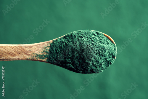 Green spirulina algae powder on a wooden spoon