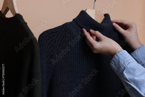 Woman taking casual sweater on beige background, closeup