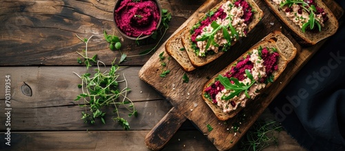 Top view of homemade rye bread sandwiches with beetroot hummus and herbs on a cutting board