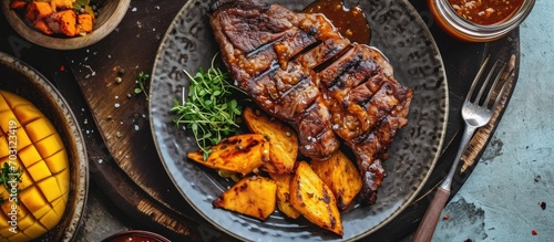 Barbecued crocodile tail fillet with roasted sweet potatoes, pineapples, and mango chutney on a plate, as seen from above.