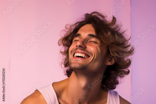 An exuberant male model laughing heartily against a soft lavender pink background.
