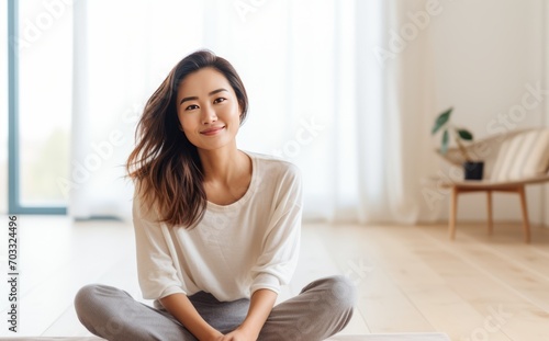 Happy Smiling Asian woman sitting cross legged on the floor and smiling. Wellness and fitness concept