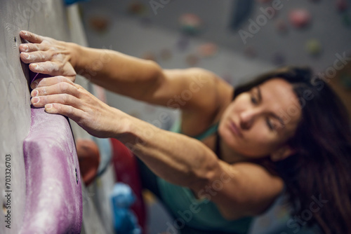 Young sportive woman, bouldering instructor with hands in powder, training, practicing indoors, climbing wall. Concept of sport, bouldering, sport climbing, hobby, active lifestyle, school, course