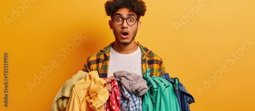 A skeptical, sarcastic young man holds laundry items, looking shocked and surprised.