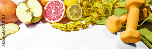 Lose weight with healthy eating, fitness and control, symbolized by fresh fruits, dumbbells and a measuring tape on a light gray background, wide panoramic format, copy space