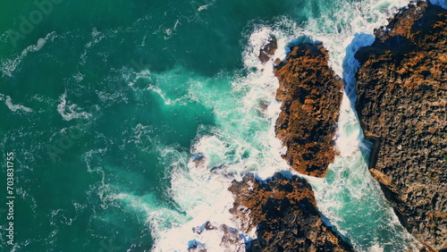 Stormy turquoise sea waves splashing at seashore cliffs. Aerial view seashore 