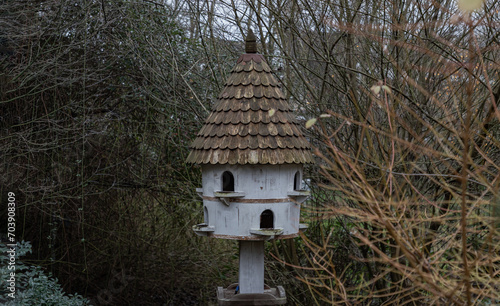 A dovecote shelter for birds and doves pigeons with multiple entrances and a pointed roof on a wooden post. Nesting sites man made by people to decorate and adorn gardens. Bird House, Handmade wooden,