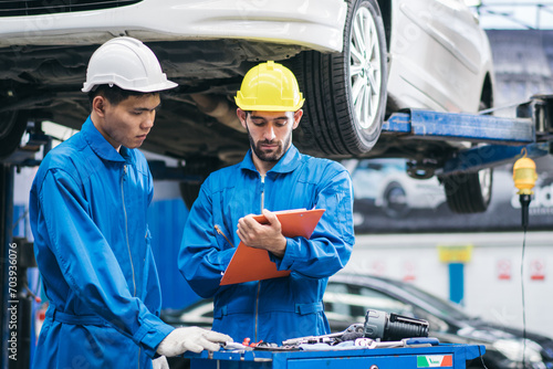 Automotive mechanic discussing on car damage checklist with assistant at auto garage shop. Transport industry, repair and maintenance career. after service after service