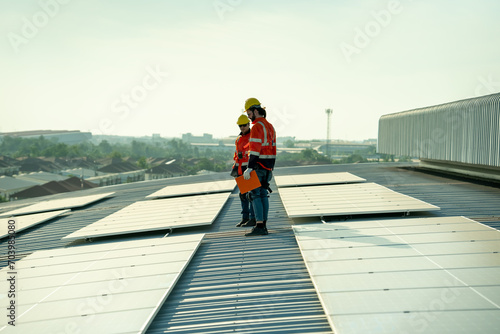 Specialist technician professional engineer checking top view of installing solar roof panel on the factory rooftop under sunlight. Engineers having service job of electrical renewable eco energy