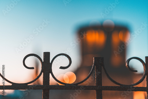 close-up photo of a curved metal barrier. blurred image of the towers of la rochelle in the background