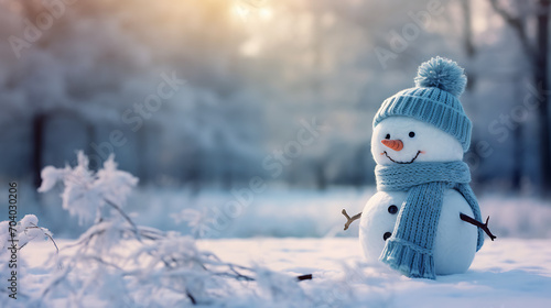 Adorable snowman wearing a blue knitted bobble hat and scarf in a winter forest, with ample copy space