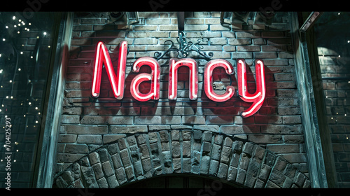 Nancy, girls name, lit up in a neon sign against brick wall