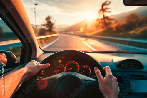 The hands of a car driver firmly gripping the steering wheel during a road trip, navigating through a highway landscape.
