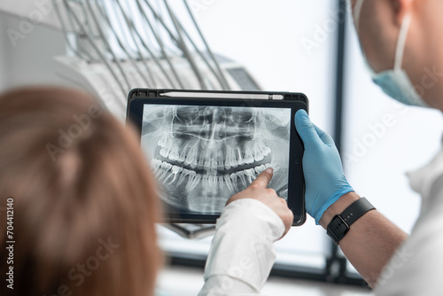 The dentist uses a tablet to visually explain the details of dental treatment so that the patient feels completely confident in her choice. Demonstrates a CT scan, an X-ray photograph