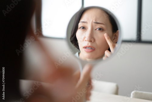 鏡を見て肌の調子が気になる女性