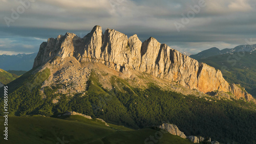 View of the majestic sheer cliff in the pre-sunset light. Mount Chertovy Vorota at sunset. Beautiful mountain landscape.