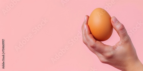 Female hand holding raw brown eggs. Spring, a product for Easter background, pastel pink easter background with copy space.
