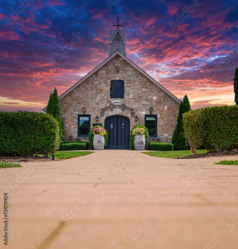 Old stone church built in 1857 with wine barrels decorated with flowers, at sunset, low angle view