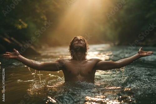 Handsome young man in worship in a river at sunset. Front view. The beauty and power of Faith. Christian concept.