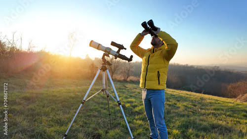 Amateur astronomer observing skies with a telescope and binoculars.