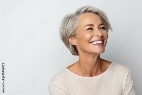 Portrait of a beautiful middle aged woman smiling and looking away against grey background